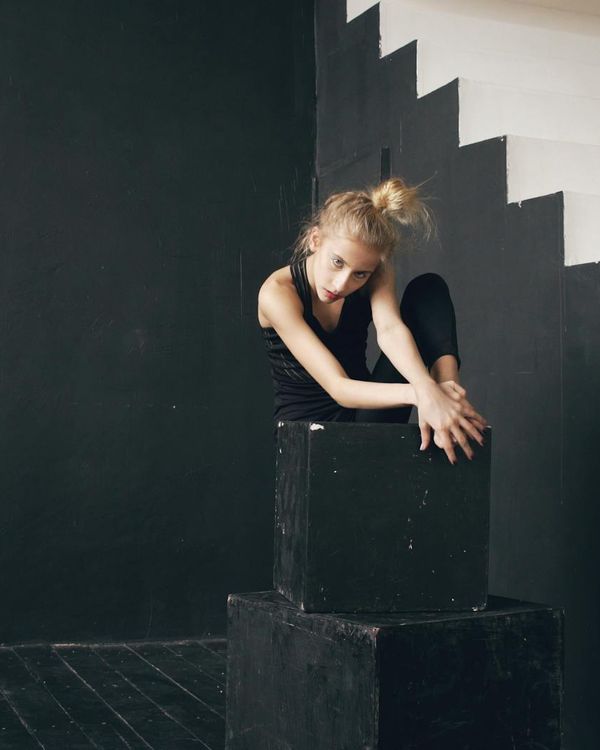 Woman performing a morning yoga pose against a dark, minimalist background with amethyst light.